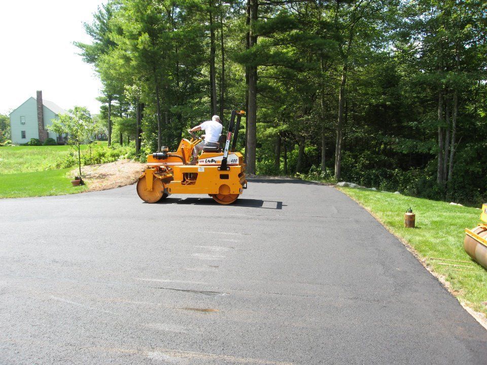 A man is driving a yellow roller on a road