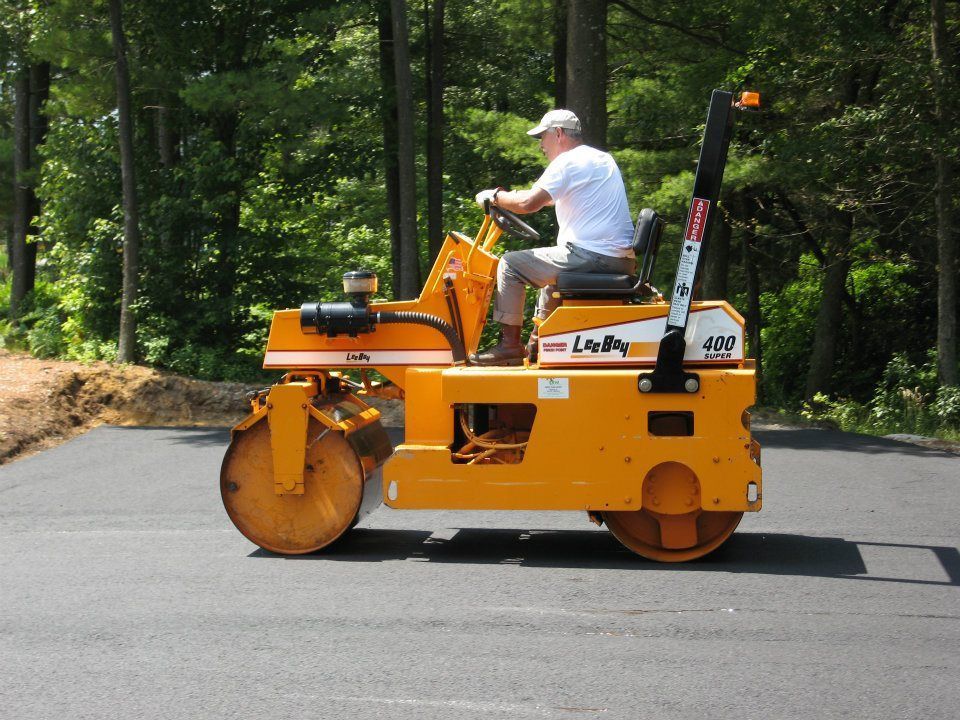 A man is driving a yellow roller on a road
