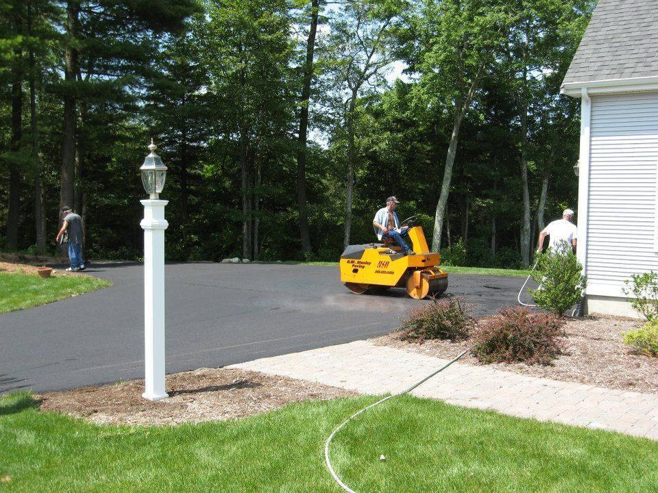 A man is driving a yellow roller on a road