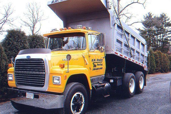 A yellow dump truck is parked on the side of the road