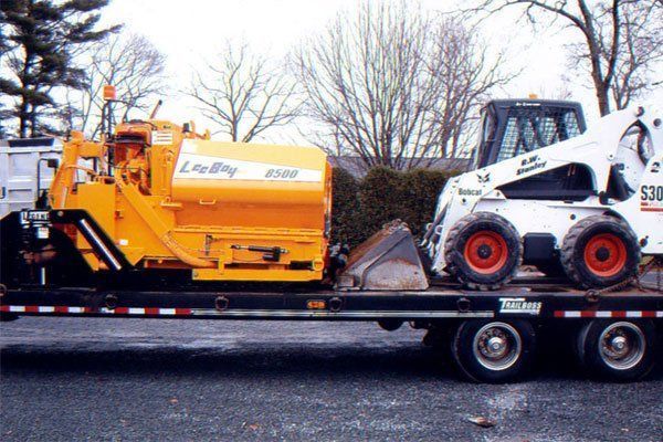 A bobcat is on the back of a flatbed truck