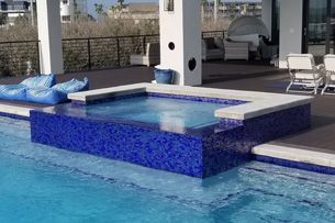 Learn More About Pool and Spas A large swimming pool with a hot tub in the middle of it