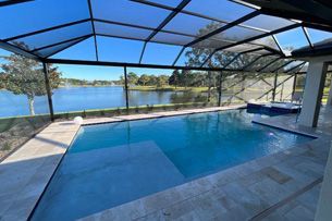 Learn More About New Pool Construction A large swimming pool surrounded by a screened in area with a view of a lake