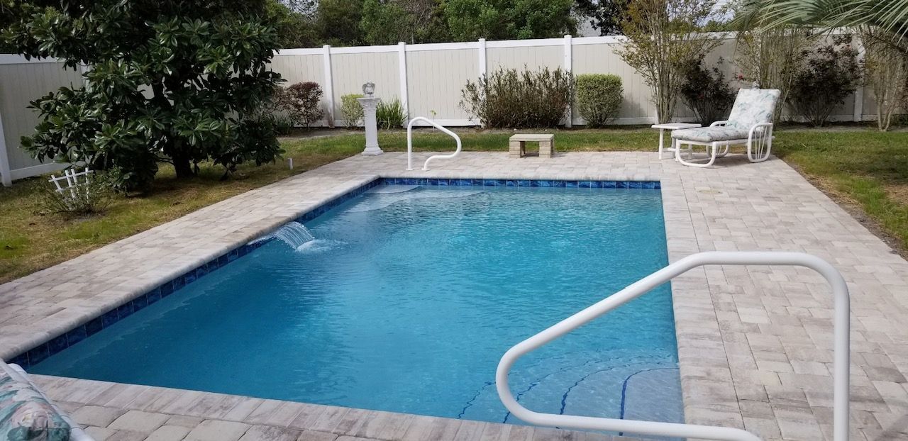 There is a large swimming pool in the backyard of a house