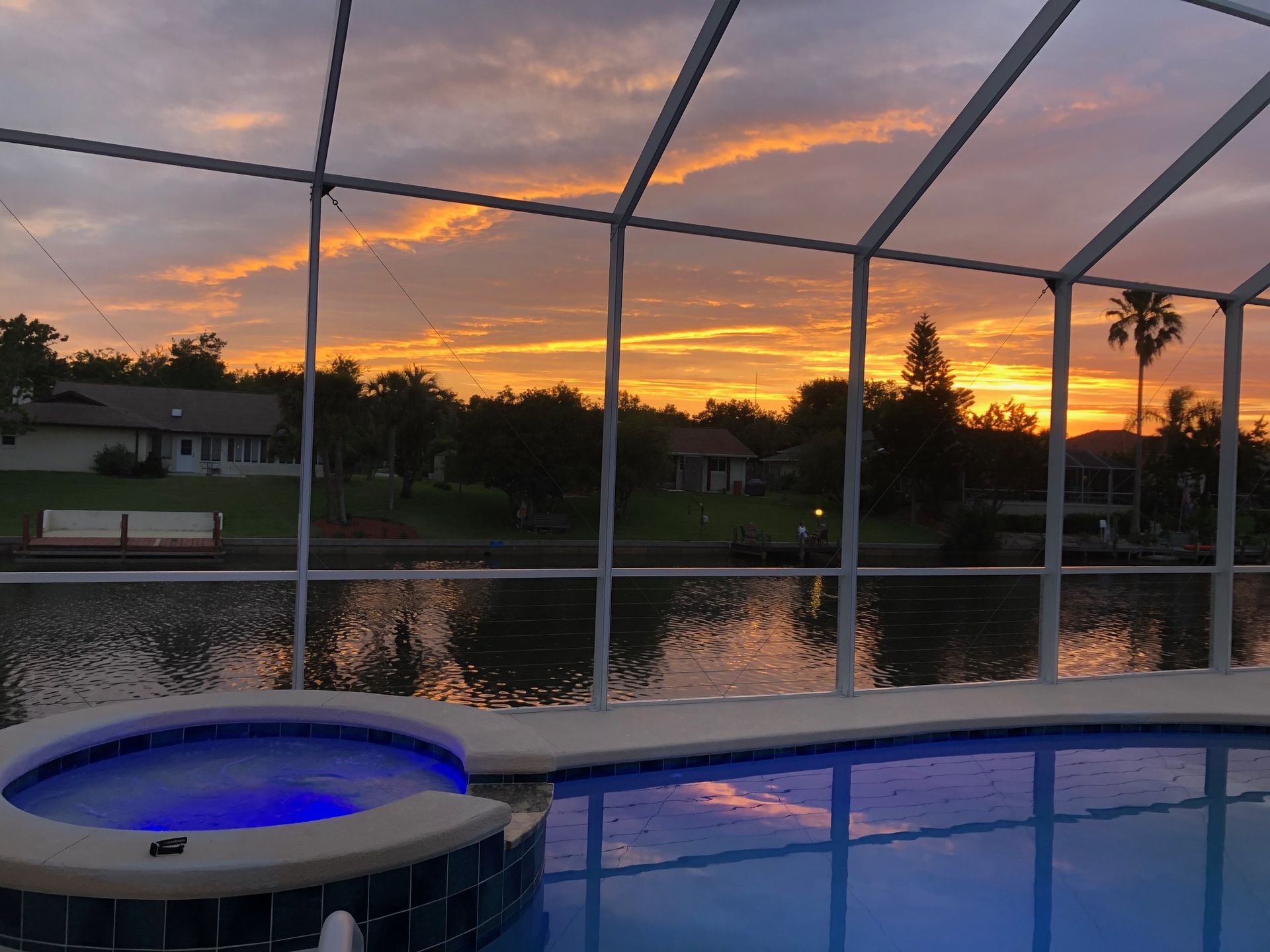 A swimming pool with a hot tub and a sunset in the background