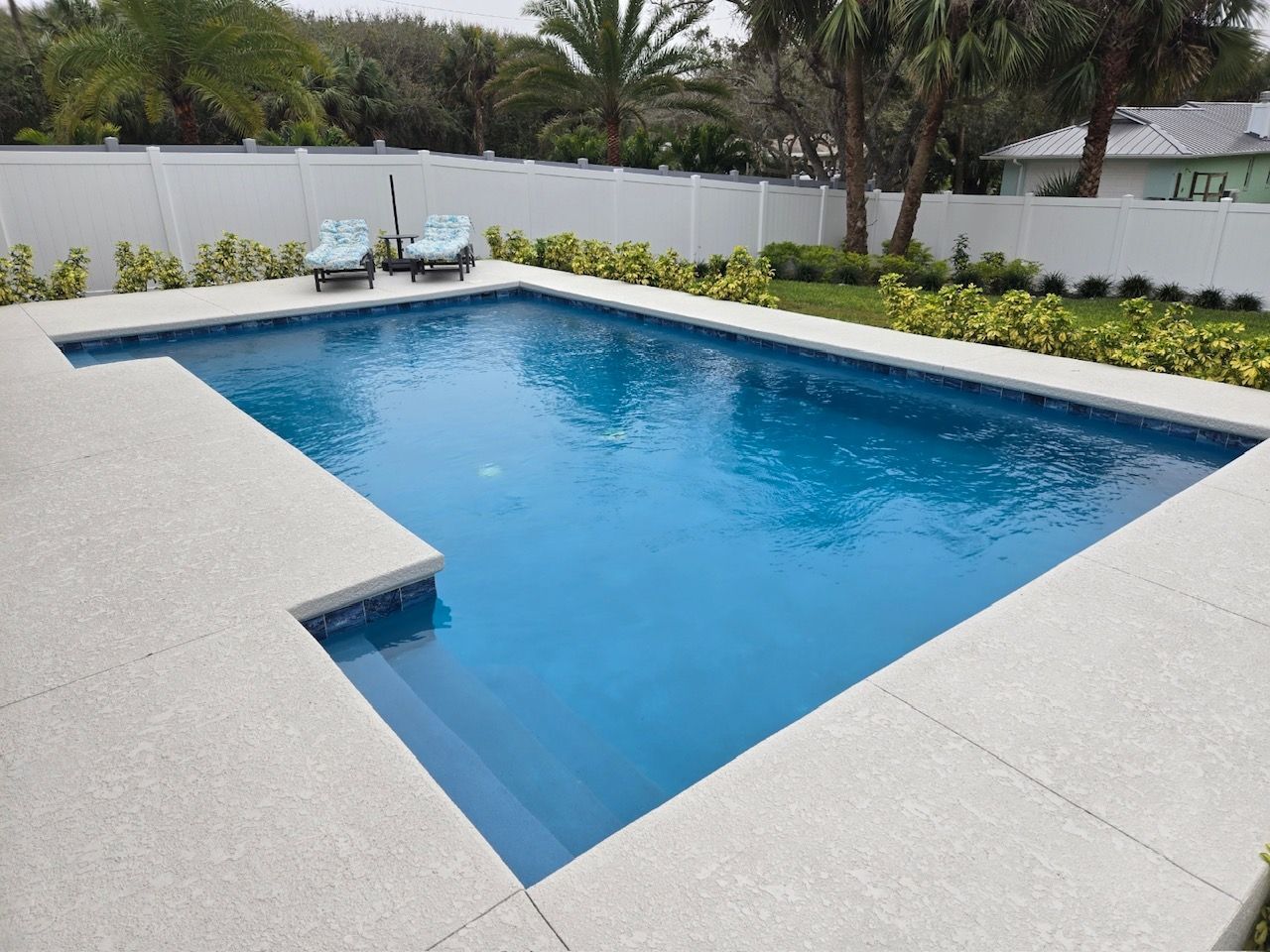 A large swimming pool with a white fence surrounding it
