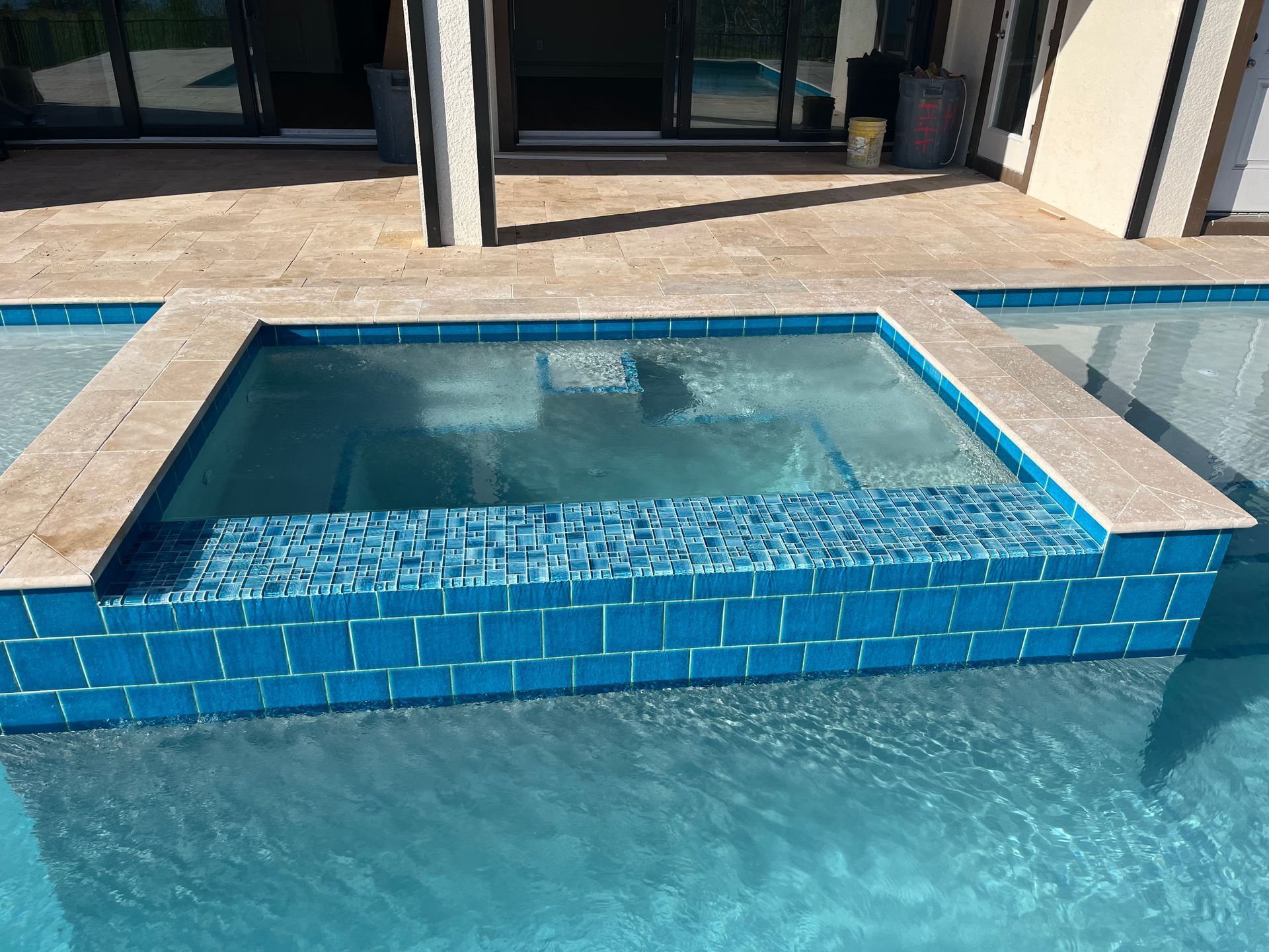 A swimming pool with tiles and a hot tub in the middle