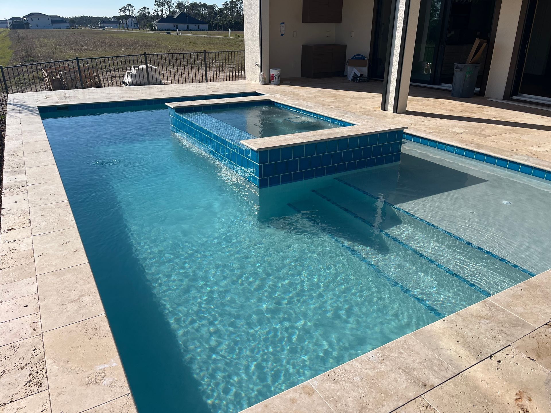 A large swimming pool with stairs and a hot tub in the middle of it