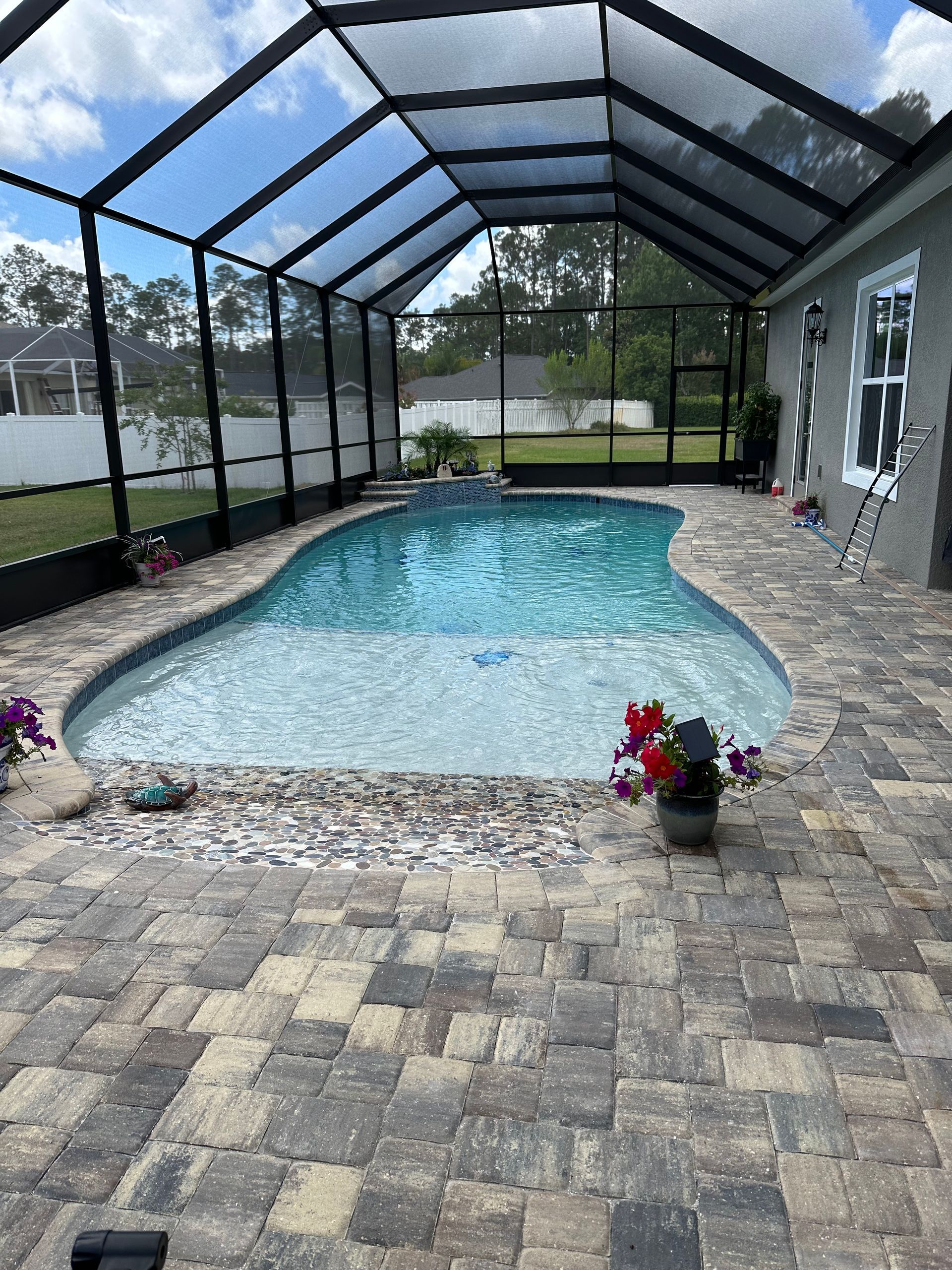 A large swimming pool with a screened in area in the backyard of a house