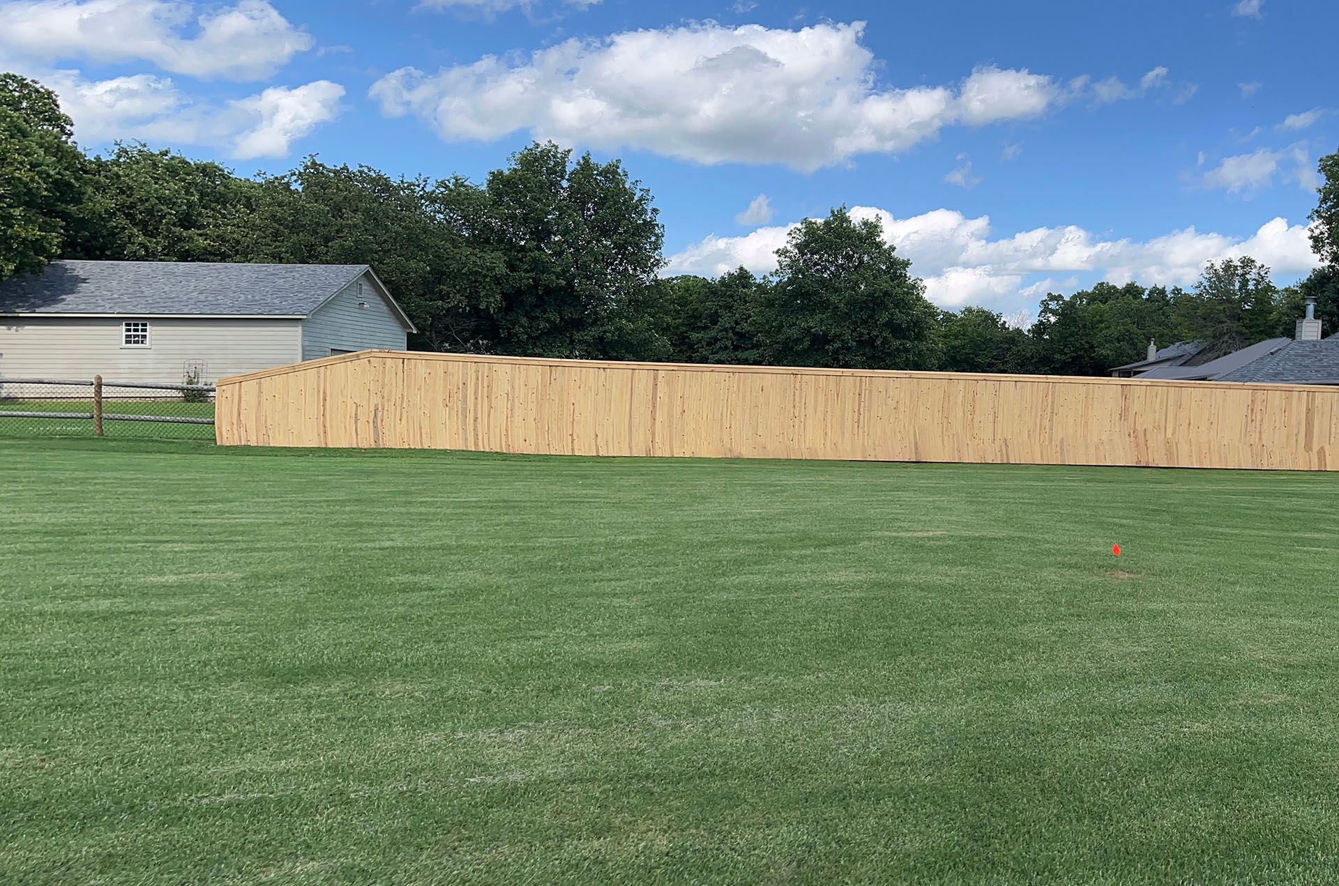 There is a wooden fence in the middle of a lush green field.