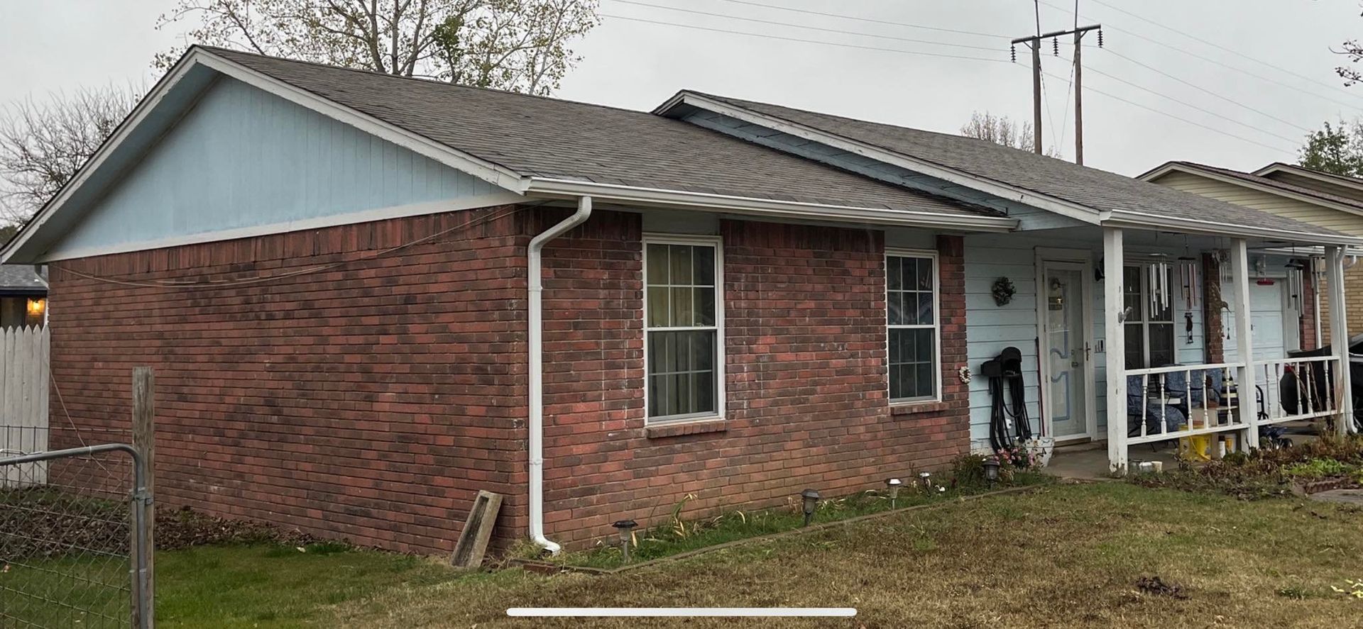 A small brick house with a blue roof and a porch.