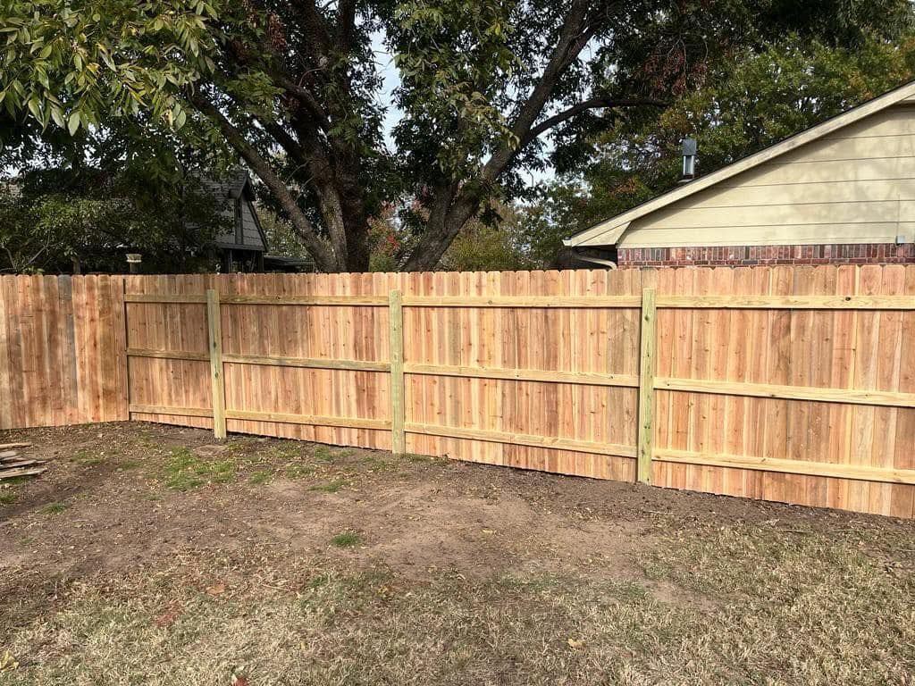 A wooden fence is in the backyard of a house.