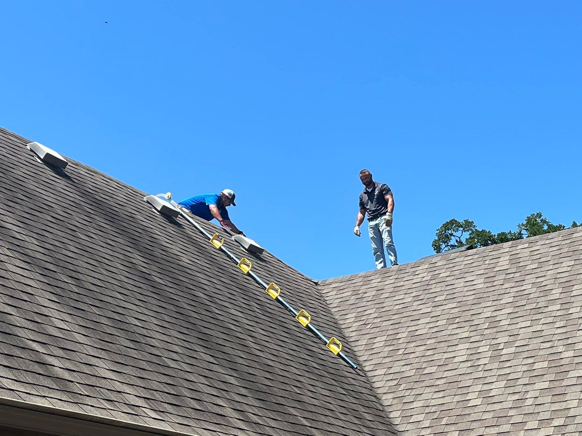 Two men are working on the roof of a house.