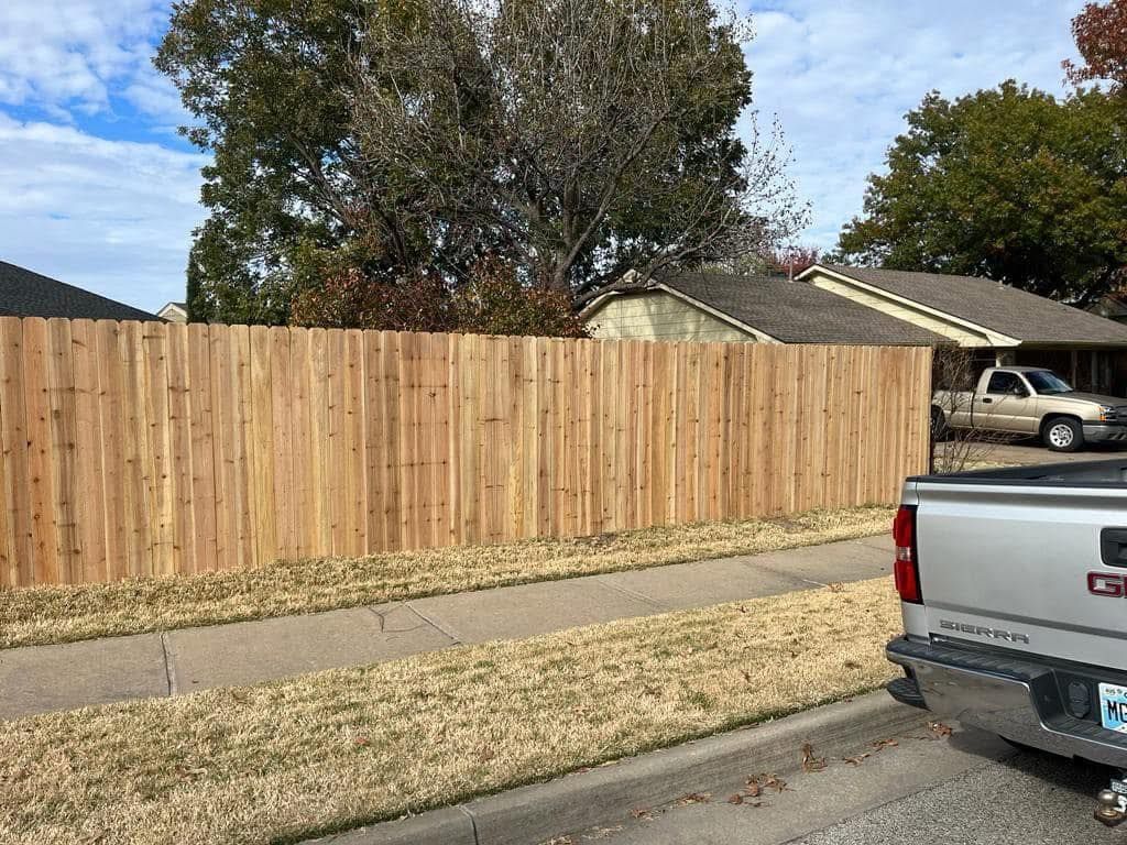 A truck is parked in front of a wooden fence.