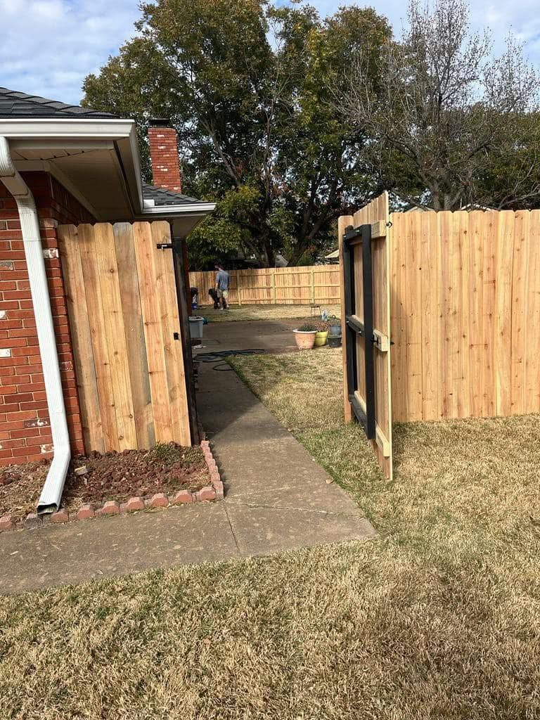 A wooden fence is being built in the backyard of a house.
