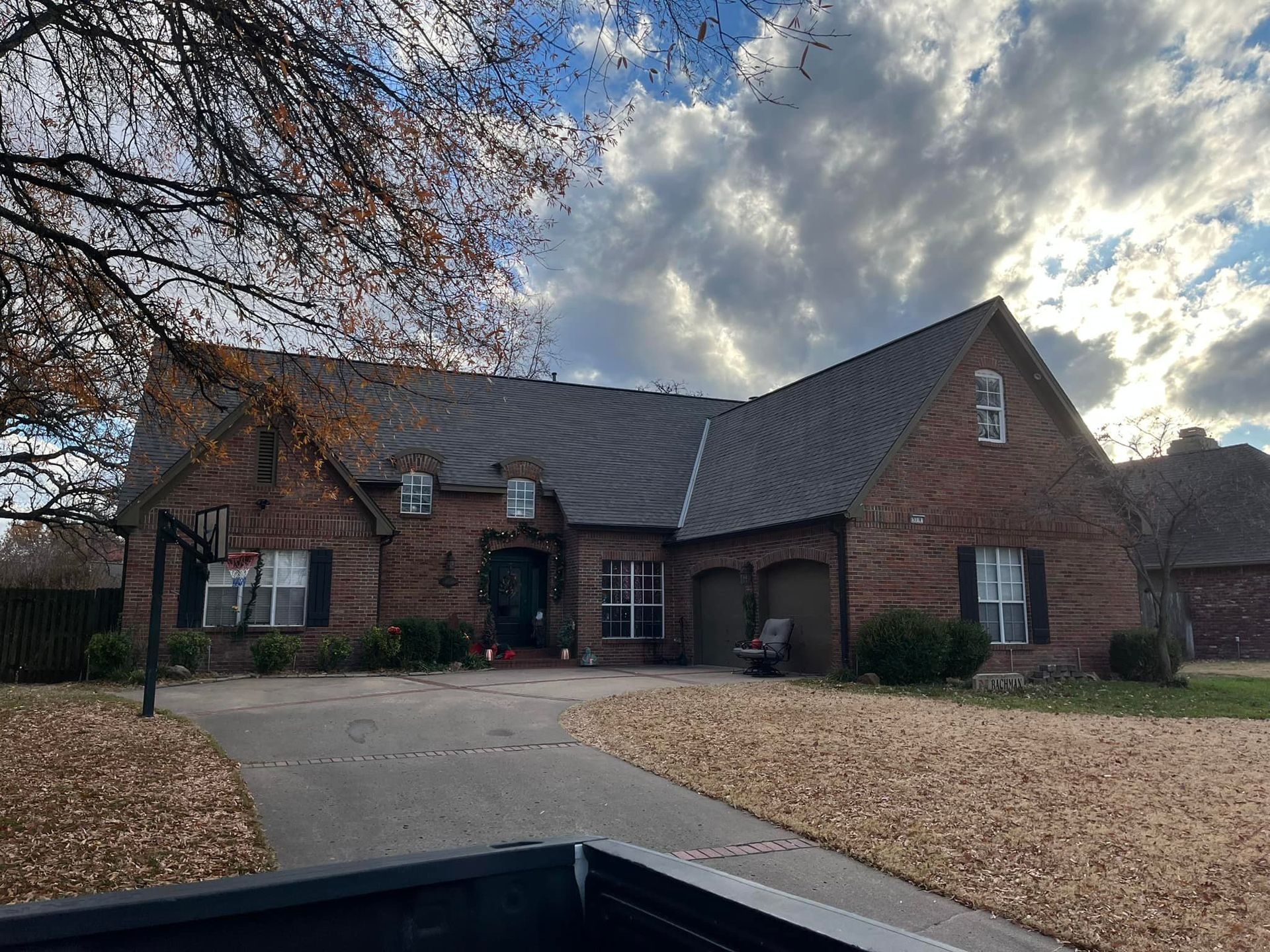A large brick house with a gray roof and a truck parked in front of it.