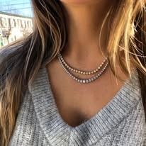 Woman wearing a gray sweater and two-strand diamond necklace.