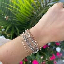 Close-up of a wrist adorned with multiple link chain bracelets in silver and gold tones.