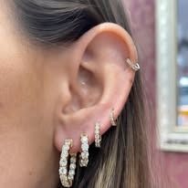 Close-up of a woman's ear adorned with multiple diamond earrings.