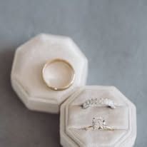 Two wedding rings in velvet ring boxes: one gold band and one diamond ring.
