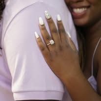 Close-up: Hand with engagement ring on a white shirt, embracing someone.