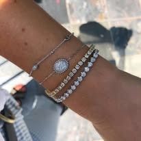 Wrist adorned with three silver bracelets, including one with diamonds.