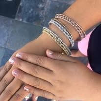 Close-up of a hand wearing three gold and silver jeweled bangles.