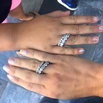 Two hands with diamond rings, one with a three-row band, the other with a two-row band.