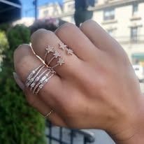 Hand wearing multiple rings, including a starburst and multi-band design, outdoors.
