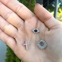 Hand holding three delicate gold necklaces with gemstones.