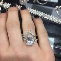 Hand wearing two diamond rings. One is a large, oval stone.