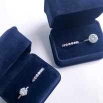 Two open blue velvet jewelry boxes with diamond rings displayed inside.