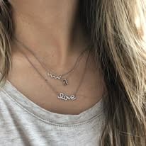 Close-up of a person's neck with two delicate necklaces, one reading 