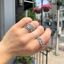 Hand with rings on fingers, next to flowers and street.