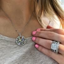 Woman wearing a pendant necklace and a diamond ring, pink nails.