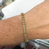 Person's wrist with a gold bracelet with small, sparkling stones.