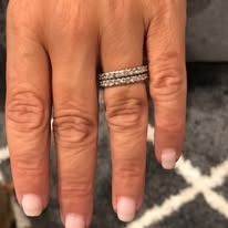 A hand wearing two diamond eternity rings.