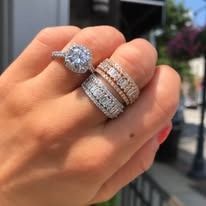 Hand wearing three diamond rings outdoors.