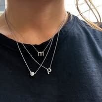 Woman wearing three layered silver necklaces with small pendants.