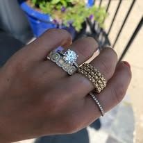 Hand wearing multiple rings, including a large diamond and a gold band.