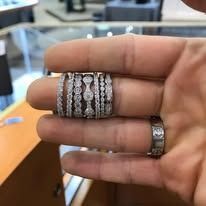 Hand holding multiple rings of different styles and sizes.