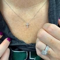 Woman wearing a cross pendant necklace and a diamond ring, close-up.