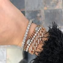 Close-up of a wrist with several diamond bracelets in white gold and rose gold.