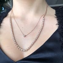 Woman wearing layered rose gold pearl necklaces.