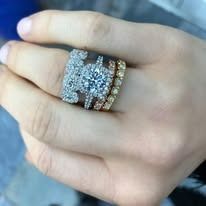 Hand wearing multiple diamond rings, including a large engagement ring.