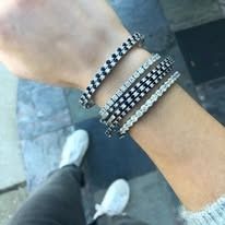 Person wearing multiple bracelets with gemstones.