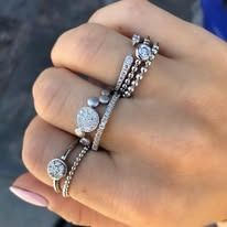 Hand wearing multiple silver rings, some with gemstones and decorative beads.