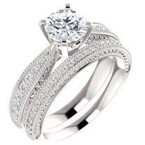 Diamond engagement ring and band set, platinum or white gold, with a round-cut center stone and pavé diamonds.
