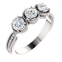 Three-stone diamond ring with a white gold band, a halo around the center diamonds, and small diamonds on the band.