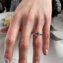 Hand wearing a silver ring with a large, faceted, grayish-white gemstone.